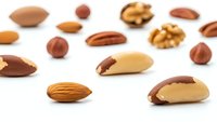 Mixed nuts collection with almonds, walnuts, hazelnuts and Brazil nuts scattered on white background for healthy snacking and cooking ingredients.