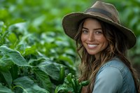 Young woman with straw hat smiling in lush green garden, showcasing sustainable farming and organic agriculture lifestyle.