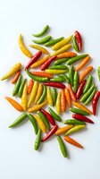 Colorful hot chili peppers scattered on white background. Fresh spicy vegetables in red, green, yellow and orange colors for cooking and culinary projects.