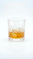Crystal cut whiskey glass with golden amber liquid isolated on white background for luxury beverage and bar design projects.