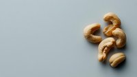 Raw cashew nuts scattered on neutral background for healthy snacking and cooking ingredients in modern kitchen design layouts.