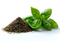 Fresh basil leaves next to pile of dried herbs on white background, showcasing contrast between fresh and dried culinary ingredients for cooking.