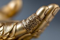 Ornate golden Buddha hand with intricate floral pattern engraving shown in macro detail against dark background, spiritual meditation and mindfulness concept.
