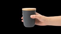 Hand holding a dark gray ceramic mug with bamboo lid, isolated on transparent background. Ready for t-shirt design, clipart, stickers, print on demand, sublimation.