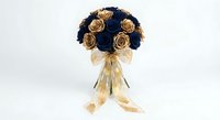 Elegant bridal bouquet of navy blue and gold roses tied with a sheer golden ribbon bow, isolated on white background.
