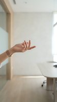 Female hand with manicured nails gesturing in modern minimalist interior space. Isolated arm showing open palm pose for wellness, communication, or acceptance concepts.
