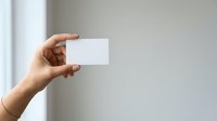 Close-up of a hand holding a blank white card against a neutral background, suitable for branding, business cards, and marketing materials.