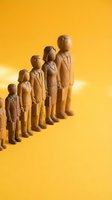 Wooden figurines of business people standing in a row on yellow background, symbolizing teamwork, hierarchy, and corporate growth.