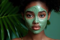 Young African American woman with green clay face mask for skincare routine and spa treatment relaxation.