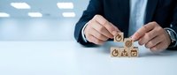 Businessman arranging wooden blocks with customer service icons on office desk for business strategy and support concept.