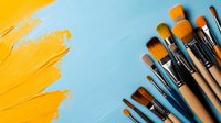 Artistic paint brushes arranged diagonally with vibrant yellow paint stroke on light blue background, creating dynamic composition for creative design projects.