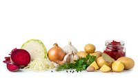 Fresh organic vegetables and ingredients for traditional borscht soup preparation including cabbage, beetroot, onions, garlic, potatoes and herbs on white background.