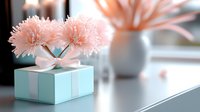 Elegant mint green gift box with white ribbon and soft pink chrysanthemum flowers on top against blurred background. Romantic celebration concept for special occasions.