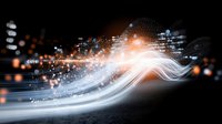 Glowing white and orange light trails with particles and bokeh effects on black background create dynamic motion and energy flow for technology designs.