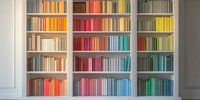 White bookshelf with colorful books arranged by spectrum, creating vibrant rainbow pattern in modern interior design for home library or office space.