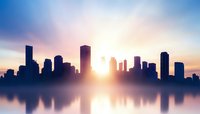Modern city skyline silhouette at sunrise with dramatic sky and water reflection creating peaceful urban landscape atmosphere for business concepts.