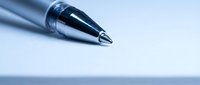 Close-up macro shot of silver ballpoint pen tip on clean white surface with shallow depth of field and soft blue lighting for business writing concepts.