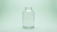 Empty clear glass jar isolated on pale green background, ready for product mockups, packaging design, storage solutions, and commercial applications.