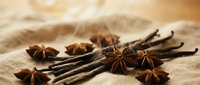 Aromatic star anise and vanilla beans arranged on neutral linen fabric, showcasing natural spices for culinary, baking, and food styling projects.