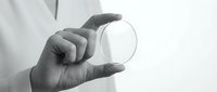 Professional hand holding transparent glass sphere against white background showcasing clarity and precision in monochrome style for business concepts.