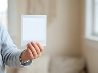 Caucasian woman holding blank white card in hand against blurred interior background, suitable for greeting cards, invitations, announcements, and marketing mockups.