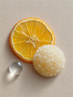 Fresh orange slice with sugar coated candy ball and water drop on beige background, minimalist food composition for culinary and dessert designs.