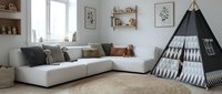 Modern Scandinavian living room interior with white sectional sofa, black teepee tent, wooden shelves, and neutral decor for family home design.