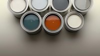 Paint cans with colorful samples for home renovation and interior design projects on neutral background.