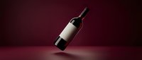 Elegant wine bottle with blank white label floating on deep burgundy background with dramatic lighting for premium branding and marketing materials.