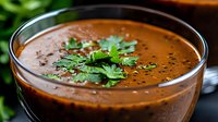 Rich tomato soup garnished with fresh herbs in metal bowl, comfort food for restaurants and home cooking menus.