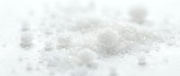 Close-up of white granulated sugar crystals scattered on surface, suitable for food photography, baking content, and culinary design projects.
