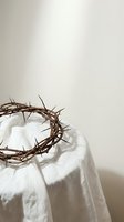 Crown of thorns resting on white linen fabric against neutral background, symbolizing sacrifice, redemption, and religious faith for Easter and Christian worship concepts.