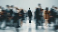 Businessman standing still in busy crowd with motion blur effect showing urban rush hour concept for leadership and standing out from masses.