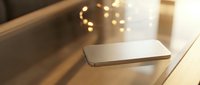 Modern smartphone lying on wooden surface with warm bokeh lights creating cozy atmosphere for technology and lifestyle concepts.