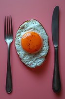 Sunny side up fried egg with crispy edges on pink background, served with vintage knife and fork cutlery set, minimalist food photography composition.