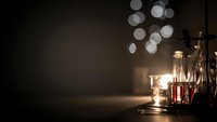 Warm candlelight creates cozy atmosphere with glowing bokeh lights and glass lanterns on dark surface for romantic evening ambiance and relaxation.