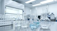 Clean laboratory glassware including beakers, flasks and test tubes arranged on white counter in modern scientific research facility for experiments.