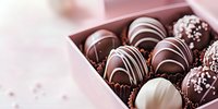 Luxury chocolate truffles with white and dark chocolate drizzle arranged in pink gift box, selective focus on gourmet confectionery against soft blurred background.