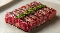Fresh raw beef steaks with rosemary herbs on cutting board ready for grilling or cooking in kitchen preparation for gourmet meal.