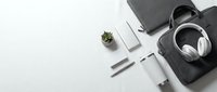 Modern minimalist workspace with laptop, headphones, and office supplies arranged on white background for business productivity and remote work concepts.