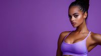 Young African American woman in purple sports bra against matching background with confident pose and glamorous makeup for fitness and beauty campaigns.