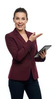 Professional businesswoman in burgundy blazer holding tablet and pointing, smiling confidently on white background for business presentations and marketing.