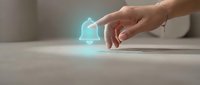 Hand touching holographic security shield icon on white surface representing cybersecurity protection and digital safety technology concepts.