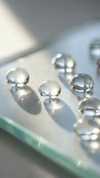 Clear glass spheres with reflective surfaces arranged on transparent glass surface creating elegant shadows and light reflections for luxury design concepts.