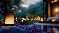 Glowing lantern among lavender flowers at dusk with soft bokeh lights creating magical garden atmosphere. Peaceful outdoor evening scene with warm illumination.