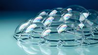 Transparent soap bubbles foam structure with iridescent rainbow reflections on blue gradient background for cleaning and hygiene concepts.