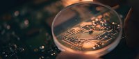 Close-up of golden cryptocurrency coin with circuit board patterns reflecting warm light on dark technological background for finance concepts.