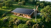 Sustainable eco-friendly house with solar panels and wind turbine in green countryside landscape for renewable energy and environmental living.