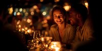 Romantic couple enjoying intimate candlelit dinner with wine glasses, warm ambient lighting creating magical atmosphere for special celebration.