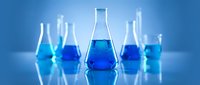 Laboratory glassware with blue chemical solutions on reflective surface for scientific research and experimentation in modern chemistry lab.